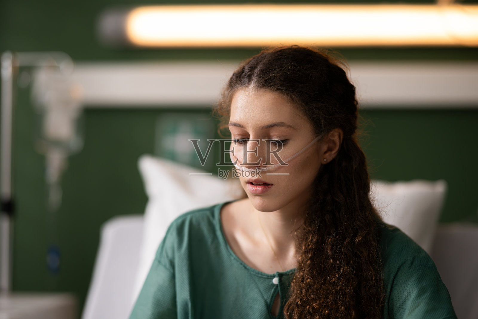 红发女孩安静地坐在床上，氧气管在身，反映了健康旅程的日常现实照片摄影图片