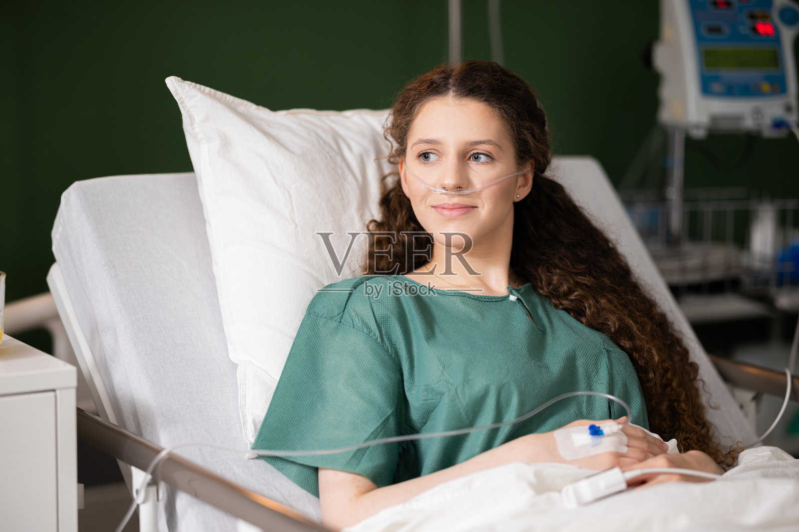 红发女孩躺在床上，手握导尿管，鼻插氧气管，在康复期间享受片刻宁静。照片摄影图片