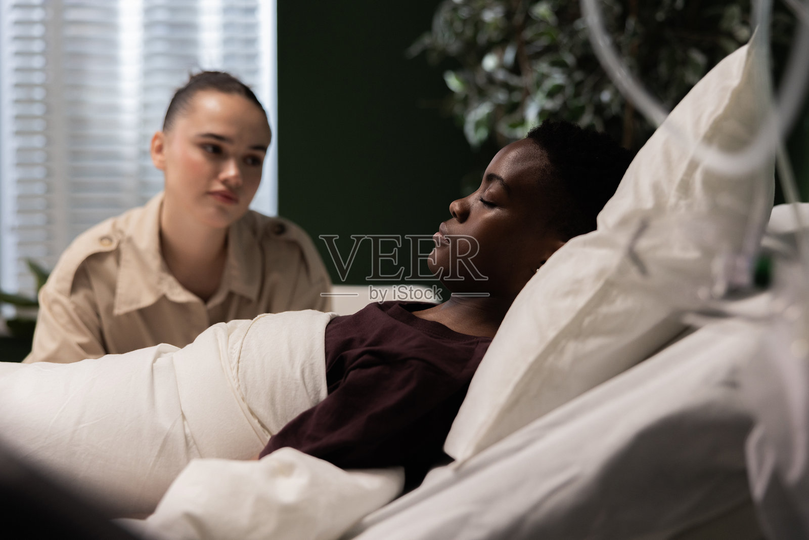 非洲患者在医院病房中安静休息，身边有朋友陪伴，正在康复中。照片摄影图片