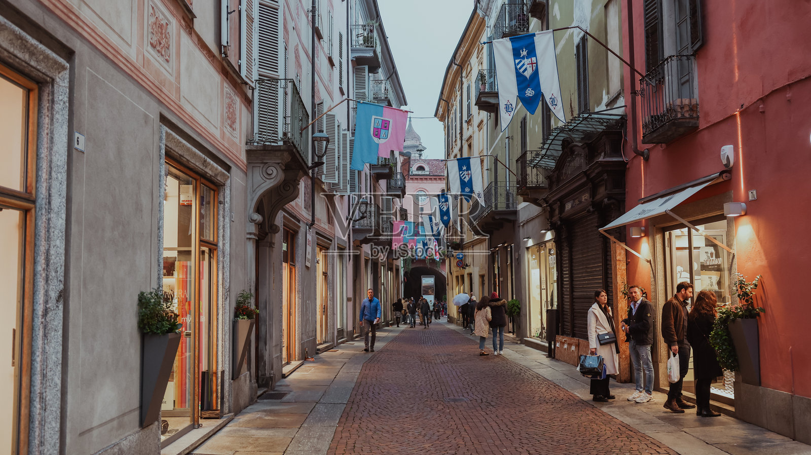 在阿尔巴迷人的街道上悠闲地散步，周围是色彩斑斓的旗帜和温馨的商店。照片摄影图片