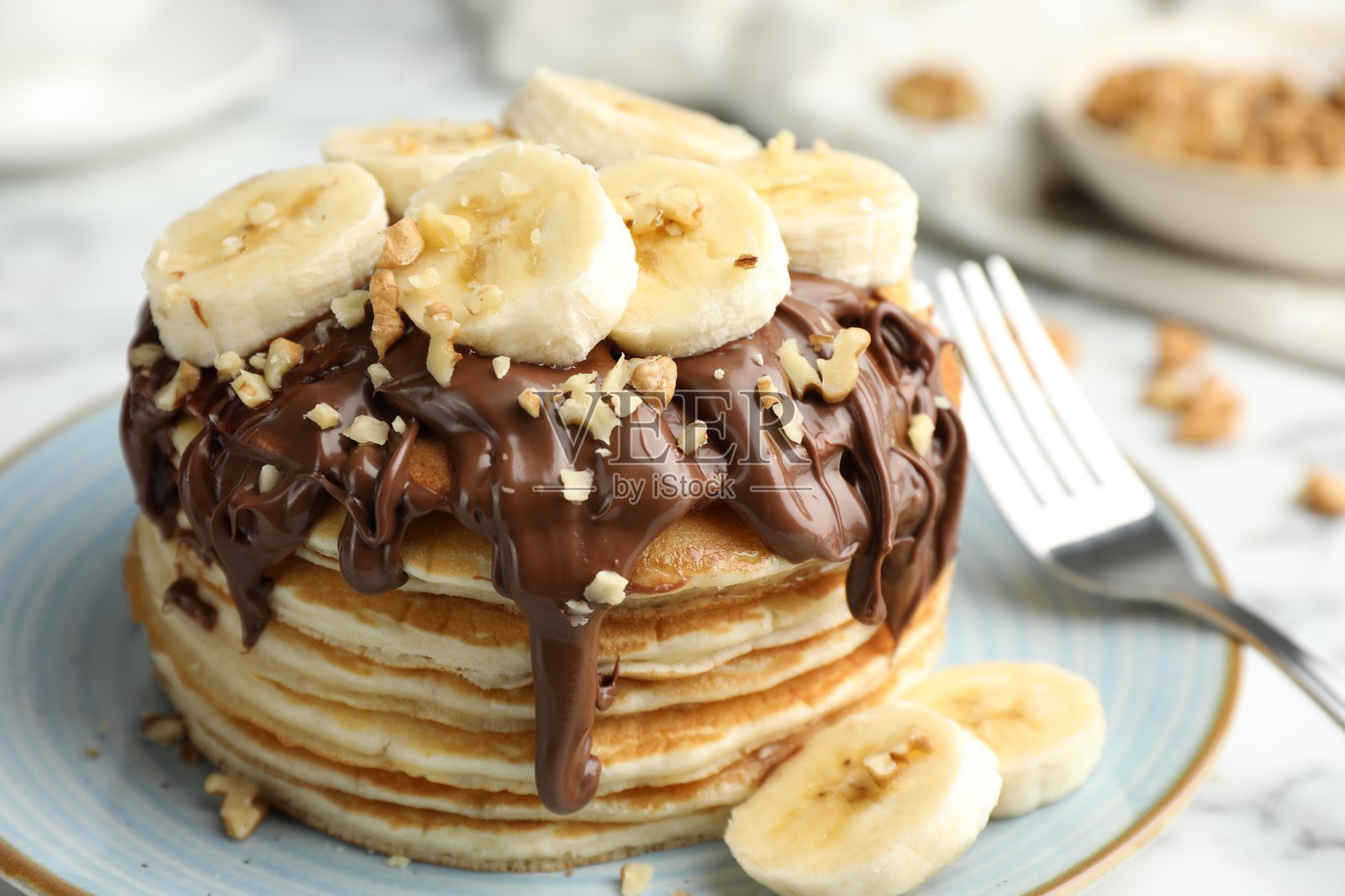 美味的煎饼配巧克力酱、切片香蕉和坚果，特写摆放在桌上照片摄影图片