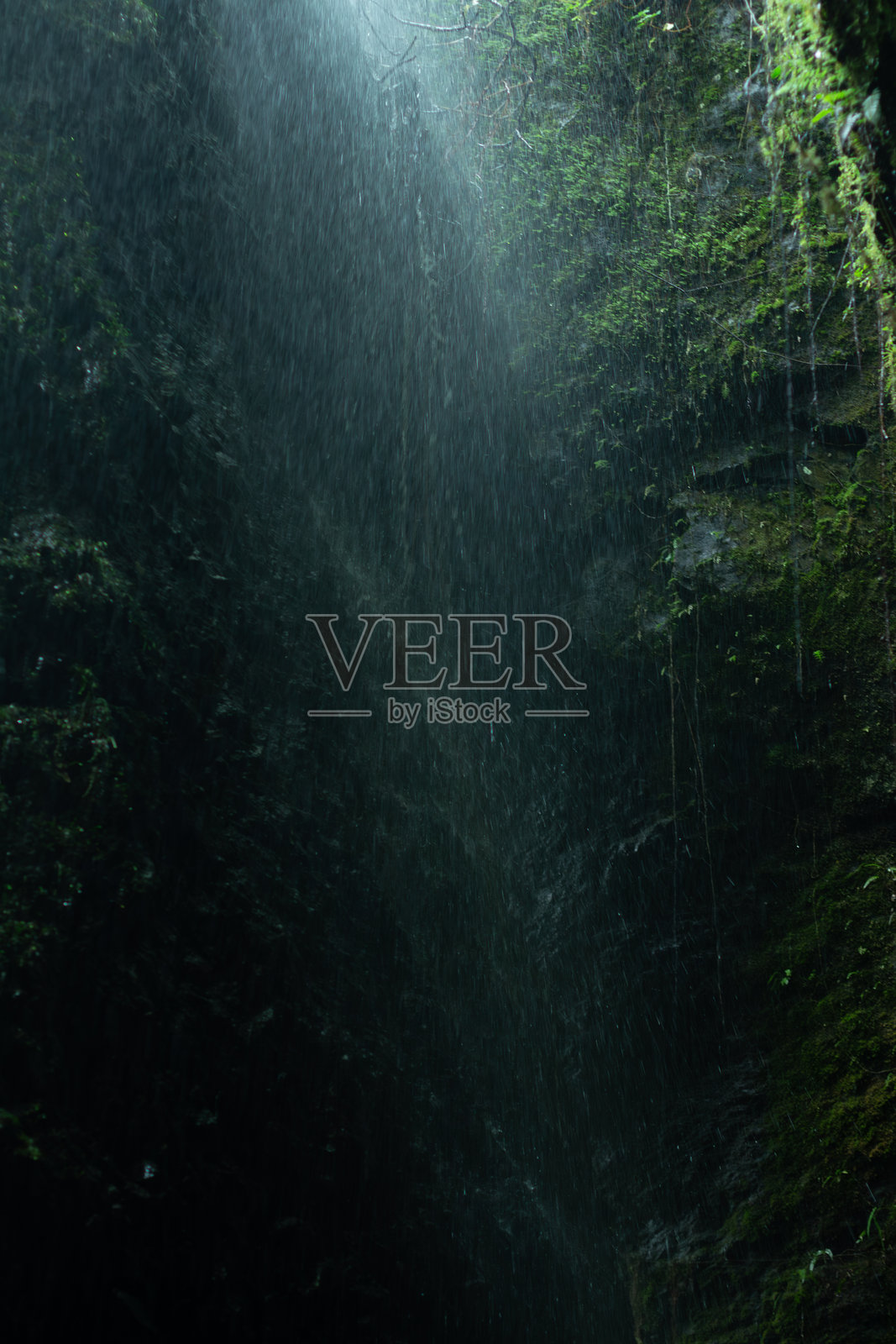 黑暗抽象画，雨水落在岩石上，水滴在光线中闪烁。照片摄影图片