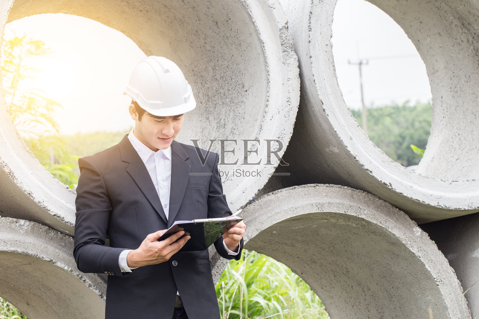 工程师在水泥管道旁阅读文件照片摄影图片
