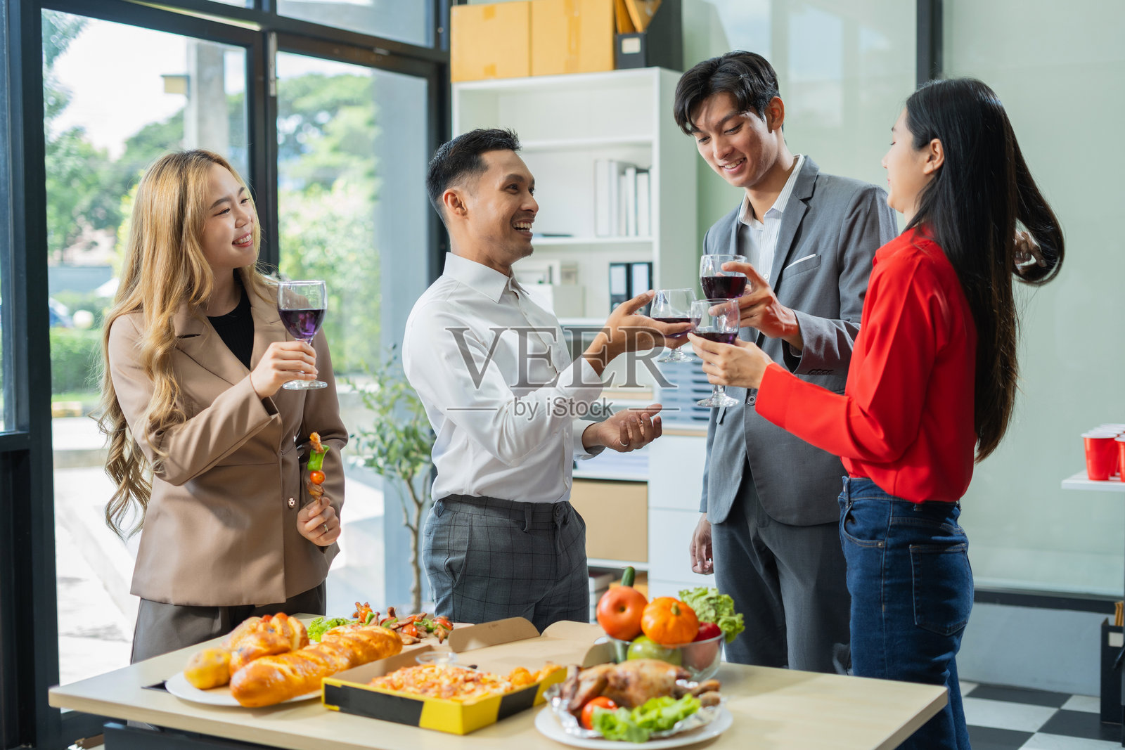 亚洲商业团队因出色的财务业绩而感到兴奋，庆祝成功交易，办公室里享用香槟和比萨。照片摄影图片