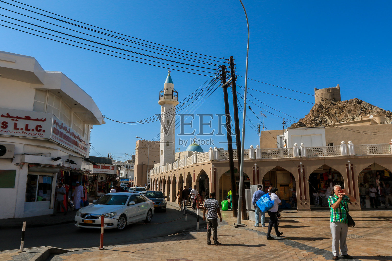 在清澈蓝天下，探索马斯喀特阿曼充满活力的街道，欣赏当地商店和清真寺。照片摄影图片