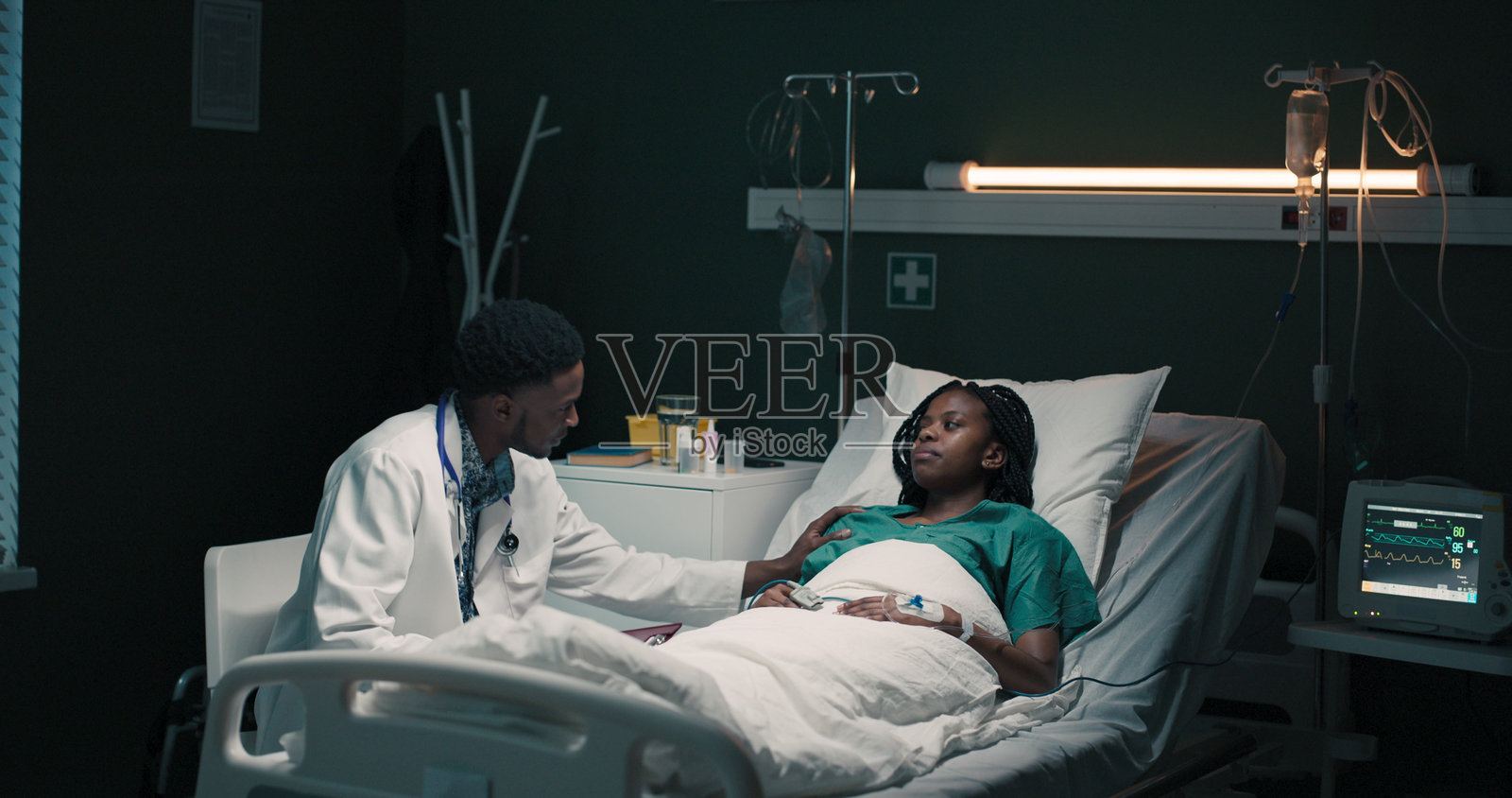 非洲医生坐在年轻非洲患者旁边，在病房里讨论她的治疗计划照片摄影图片