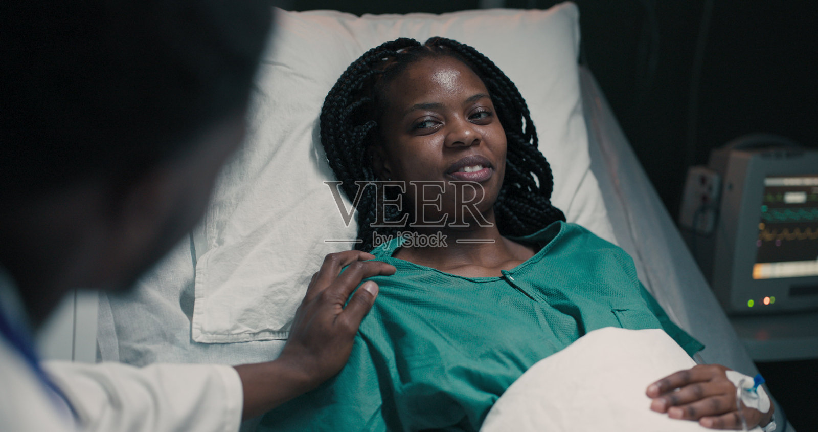 年轻的非洲医生坐在医院病房的病床旁照片摄影图片