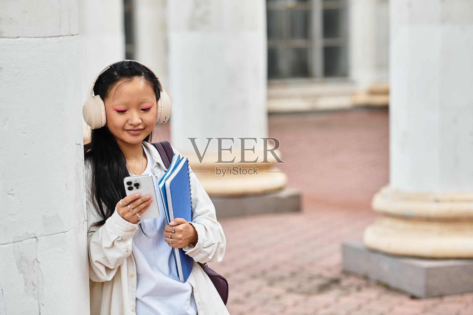 一位穿着时尚的年轻亚洲学生在大学校园附近享受时光照片摄影图片