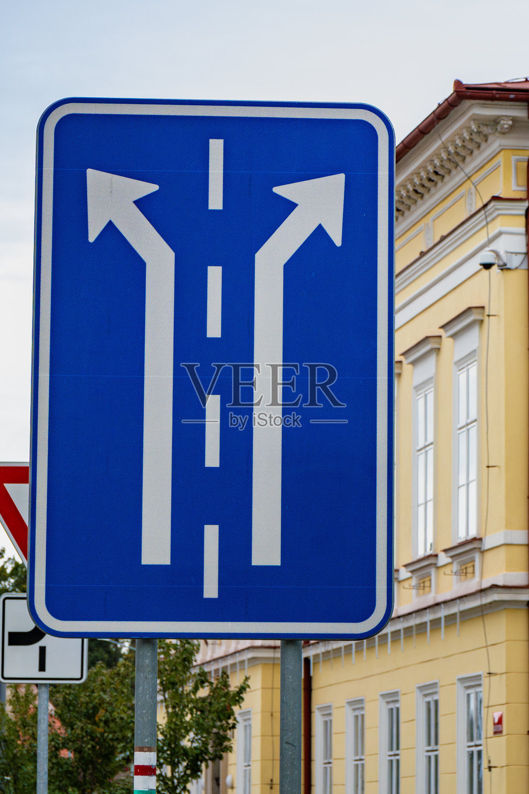 捷克的路标指示两个方向选择，背景是白天的黄色建筑。照片摄影图片