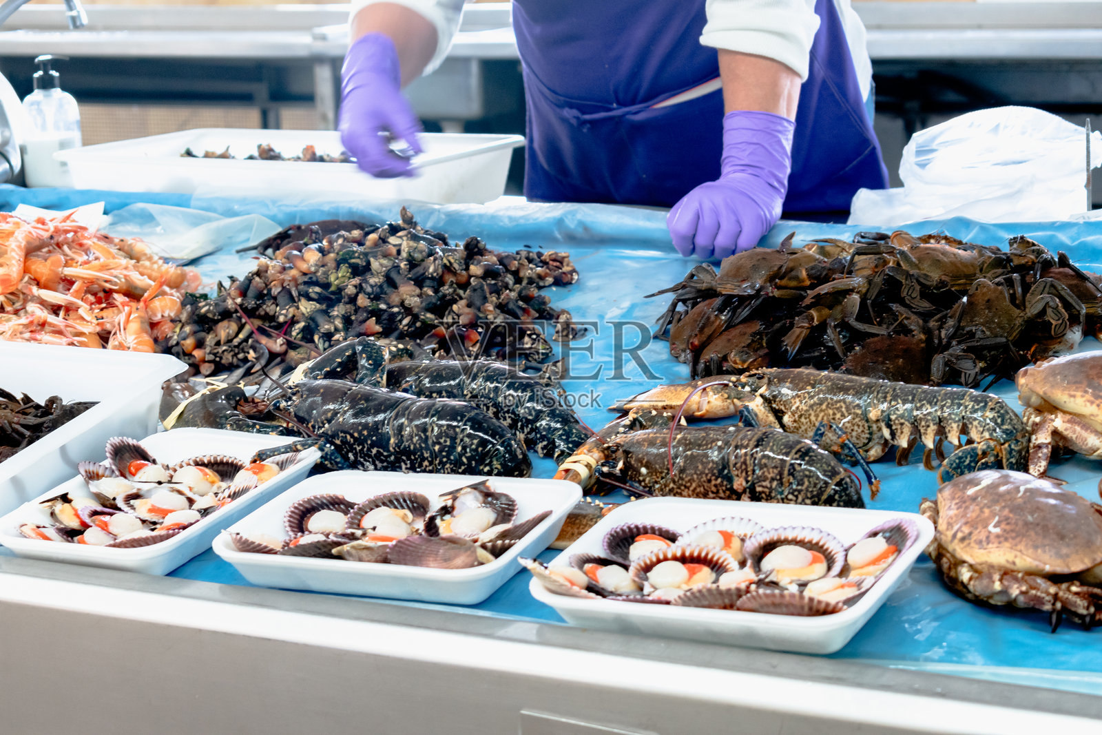 在当地市场的海鲜摊位上，一位无法辨认的鱼贩。鱼市。照片摄影图片