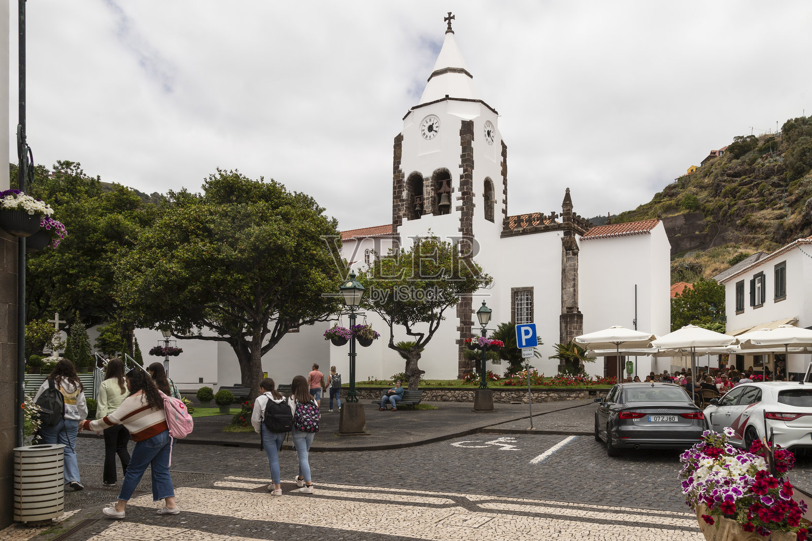 背着书包的学生走过位于马德拉圣克鲁斯市的圣十字教堂 - 圣萨尔瓦多教堂。照片摄影图片