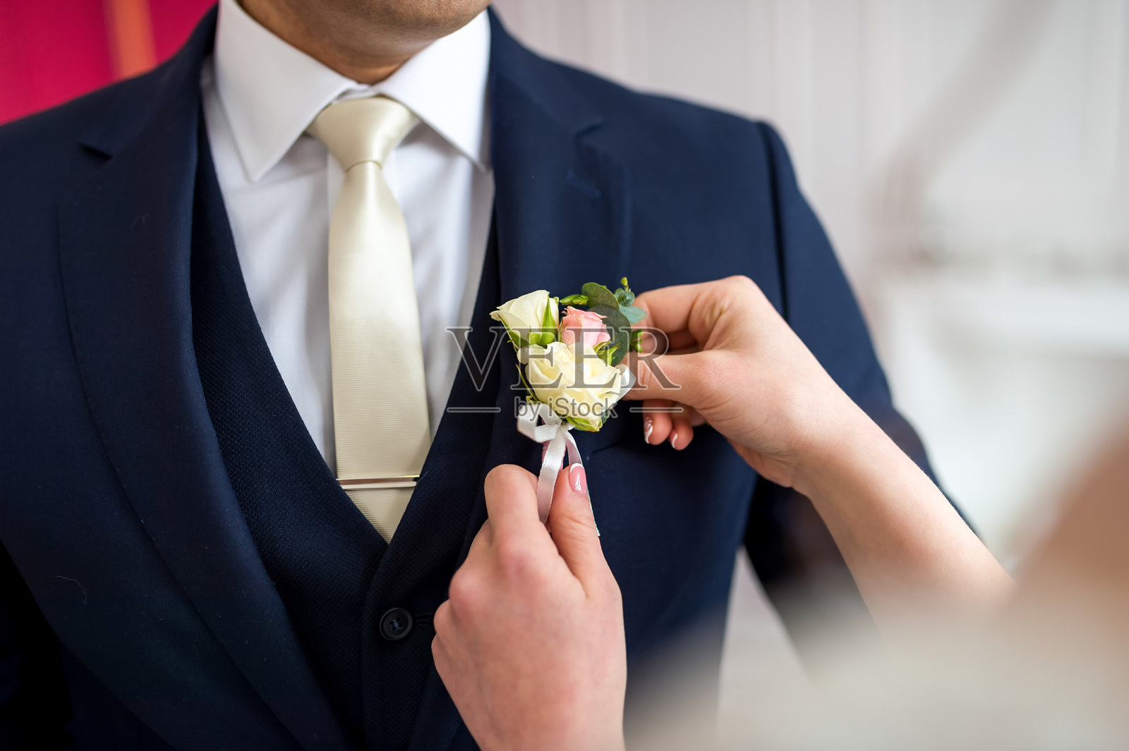 在一场深刻的服装艺术展示中，一位身穿西装的男士轻柔地为另一位男士别上胸花。照片摄影图片