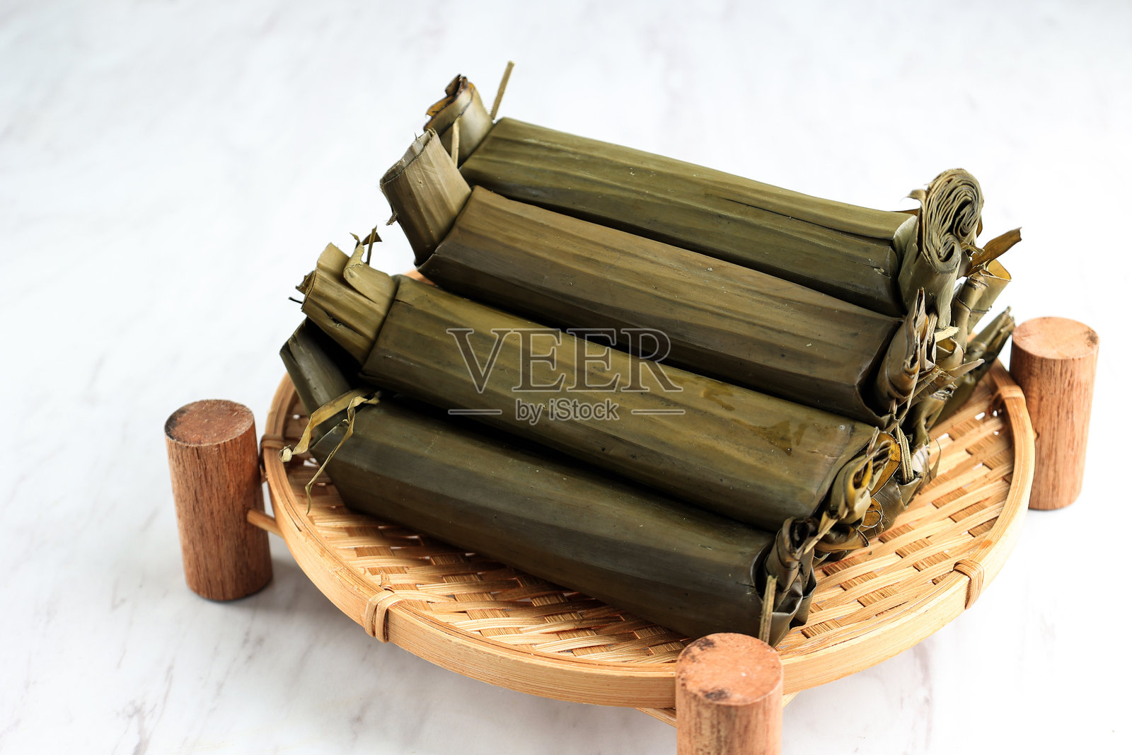 印尼香蕉叶包裹的米糕隆通，放在藤制盘子上照片摄影图片