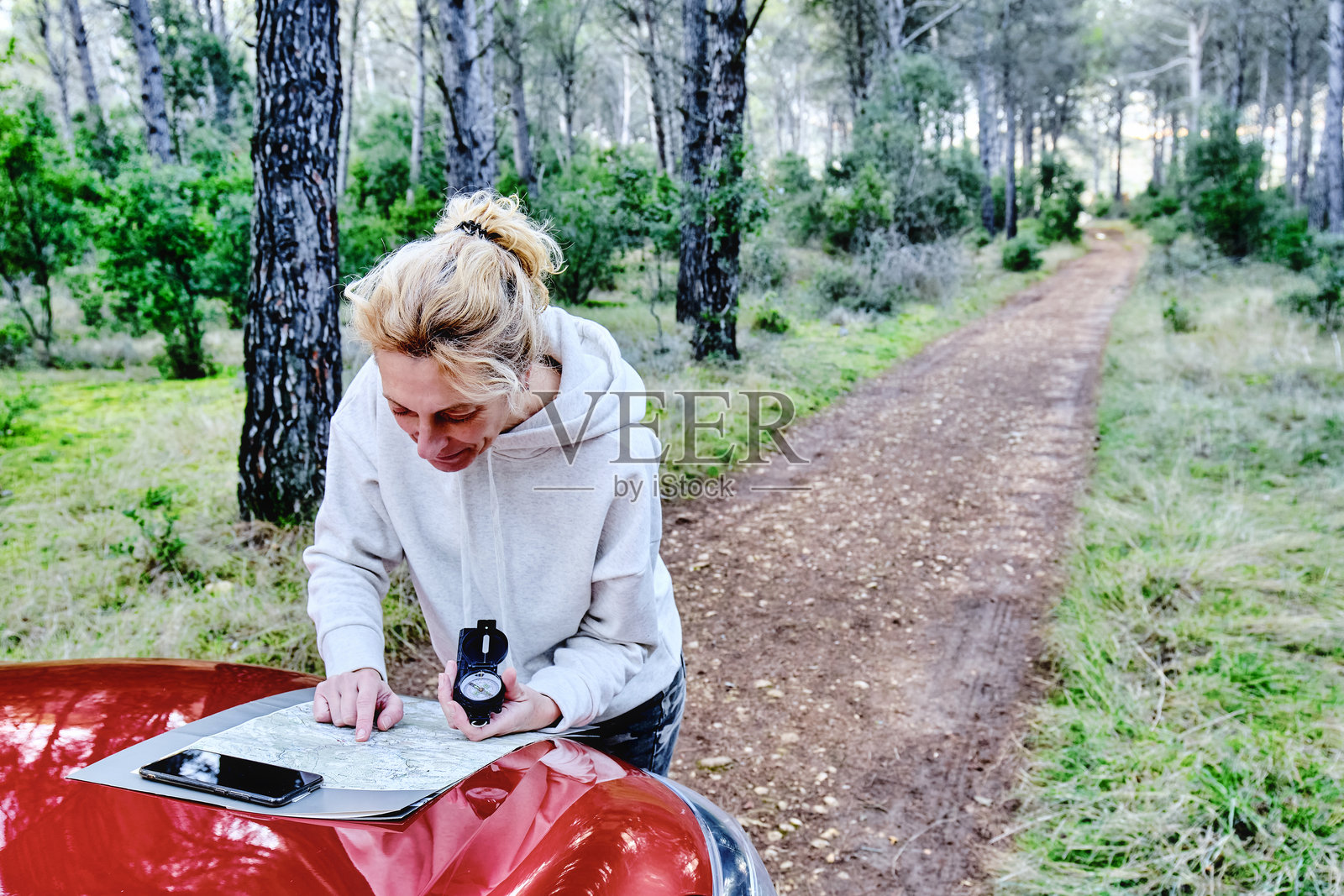 一名女性在森林中靠近汽车，使用地图和指南针进行定位。照片摄影图片