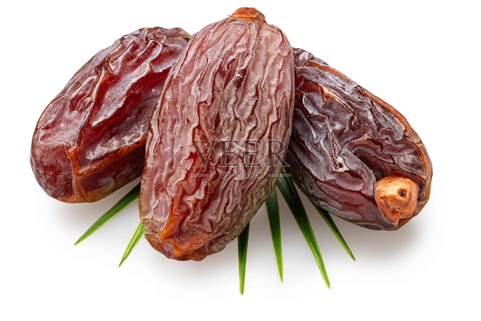 半干枣或枣椰果躺在棕榈叶上，背景为白色。文件包含抠图路径。照片摄影图片