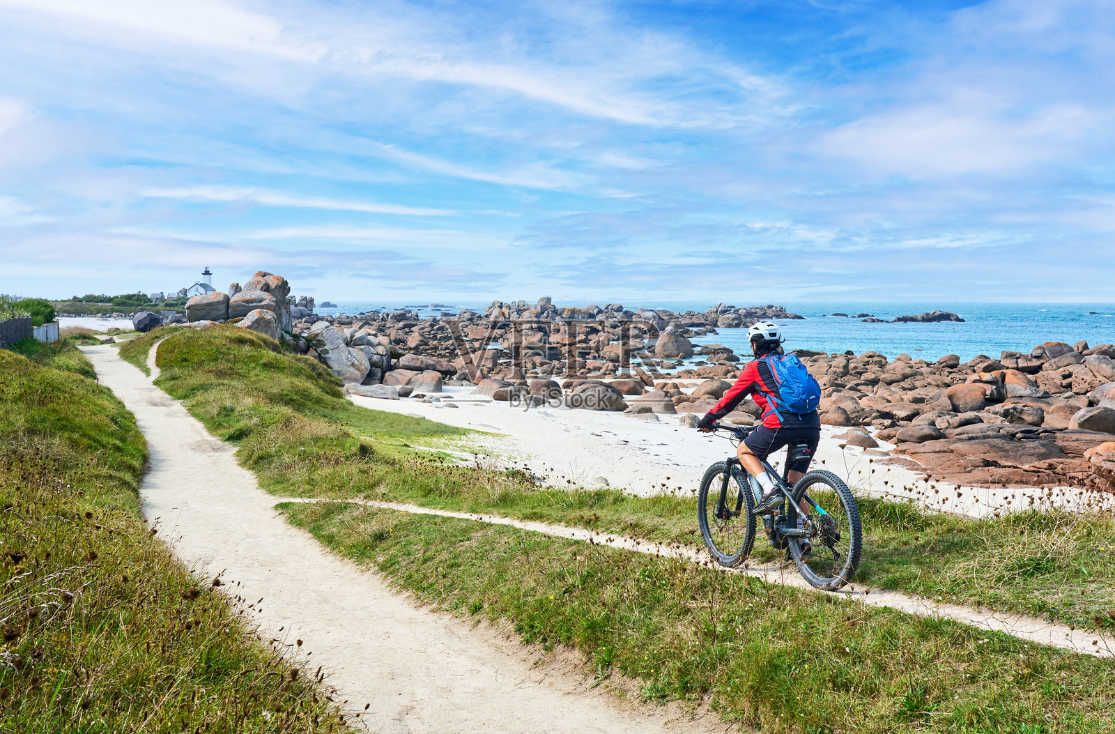 在法国布列塔尼的玫瑰花岗岩海岸骑自行车的女性照片摄影图片