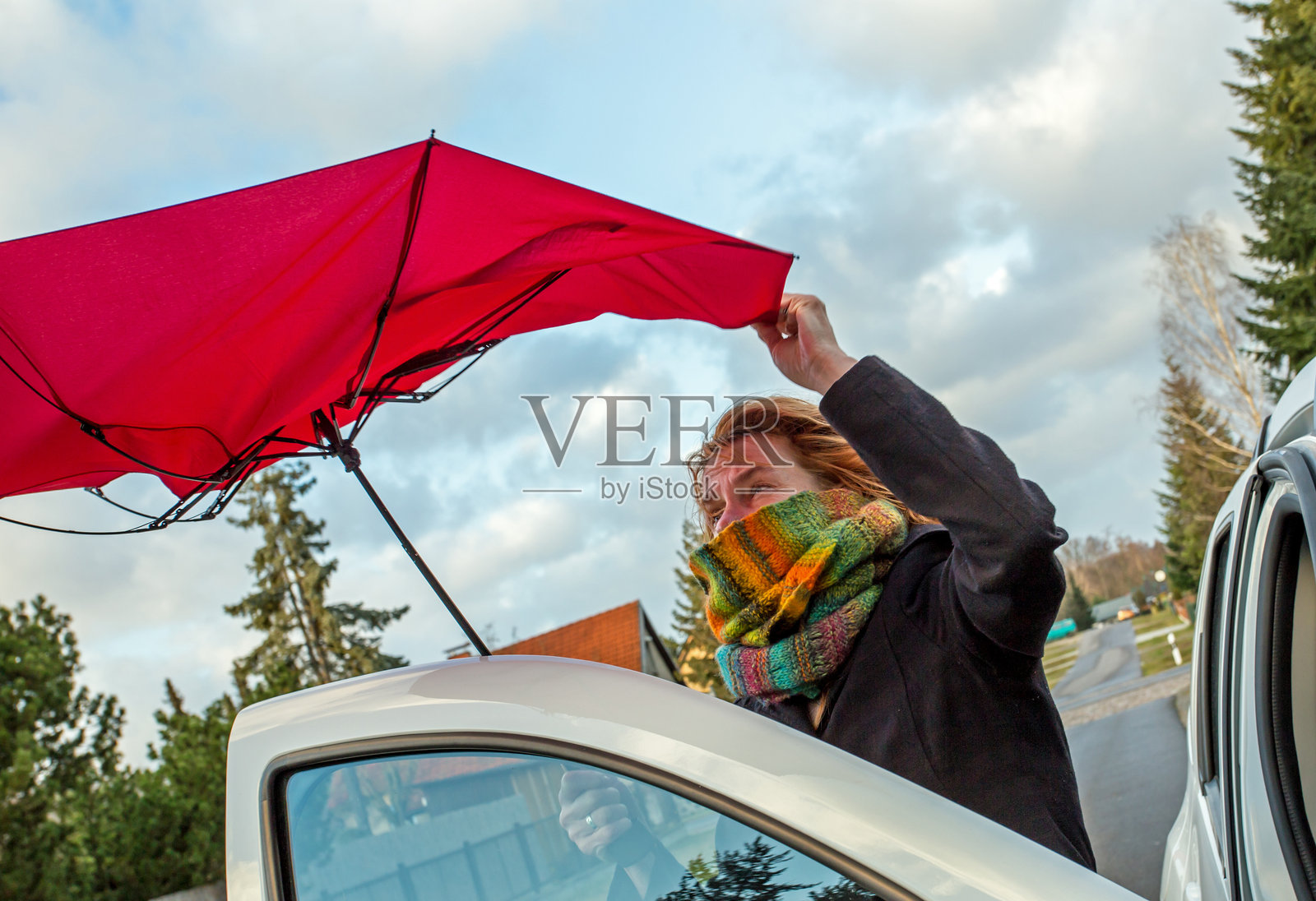 手持红伞的女人站在车旁照片摄影图片