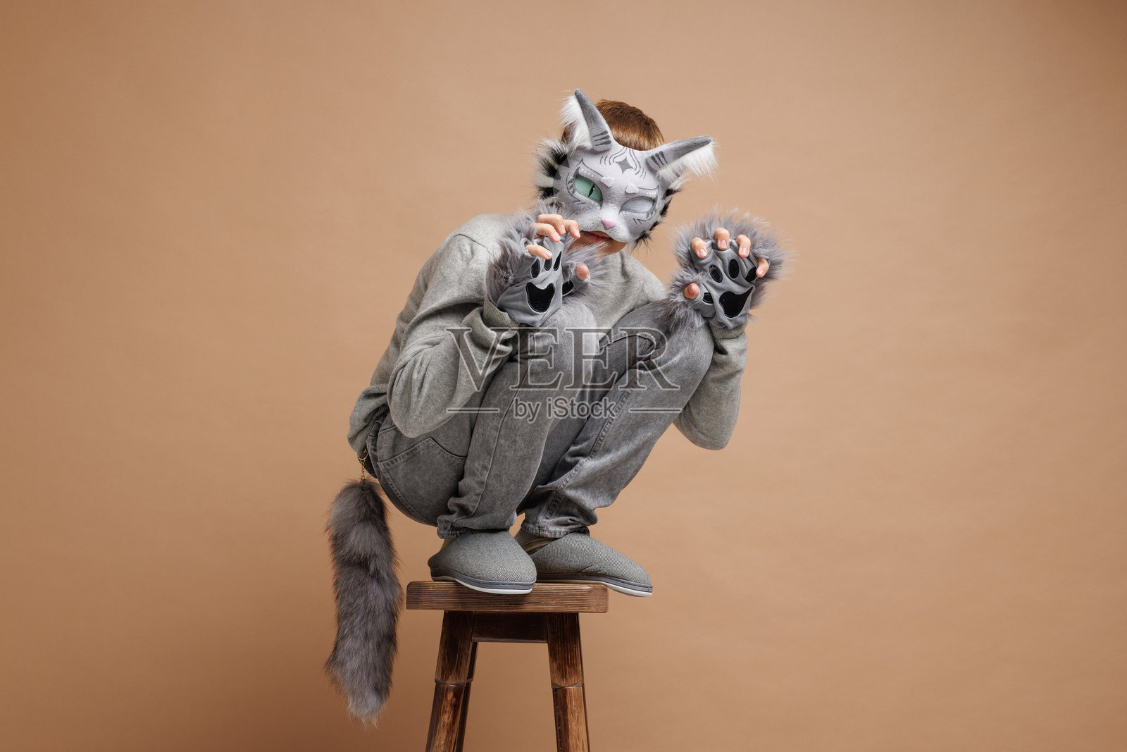 四足健身肖像，穿着猫面具的青少年在米色背景下，摄影棚照片。照片摄影图片