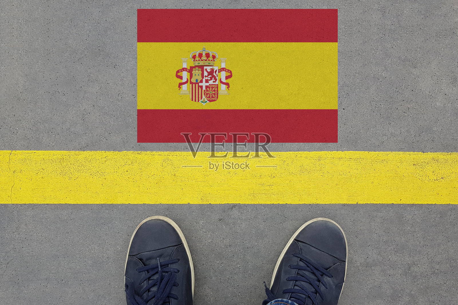 在沥青道路上，西班牙国旗和穿鞋的腿。西班牙移民与旅行概念照片摄影图片