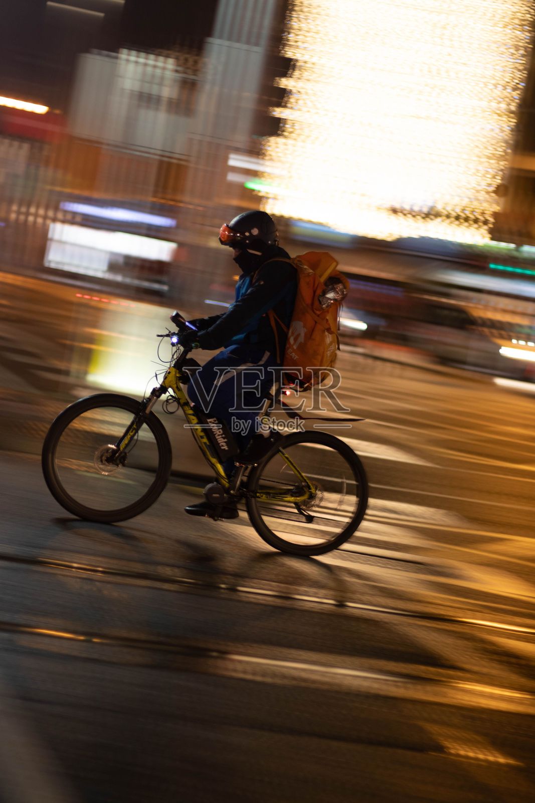 城市灯光下骑行的快递员照片摄影图片
