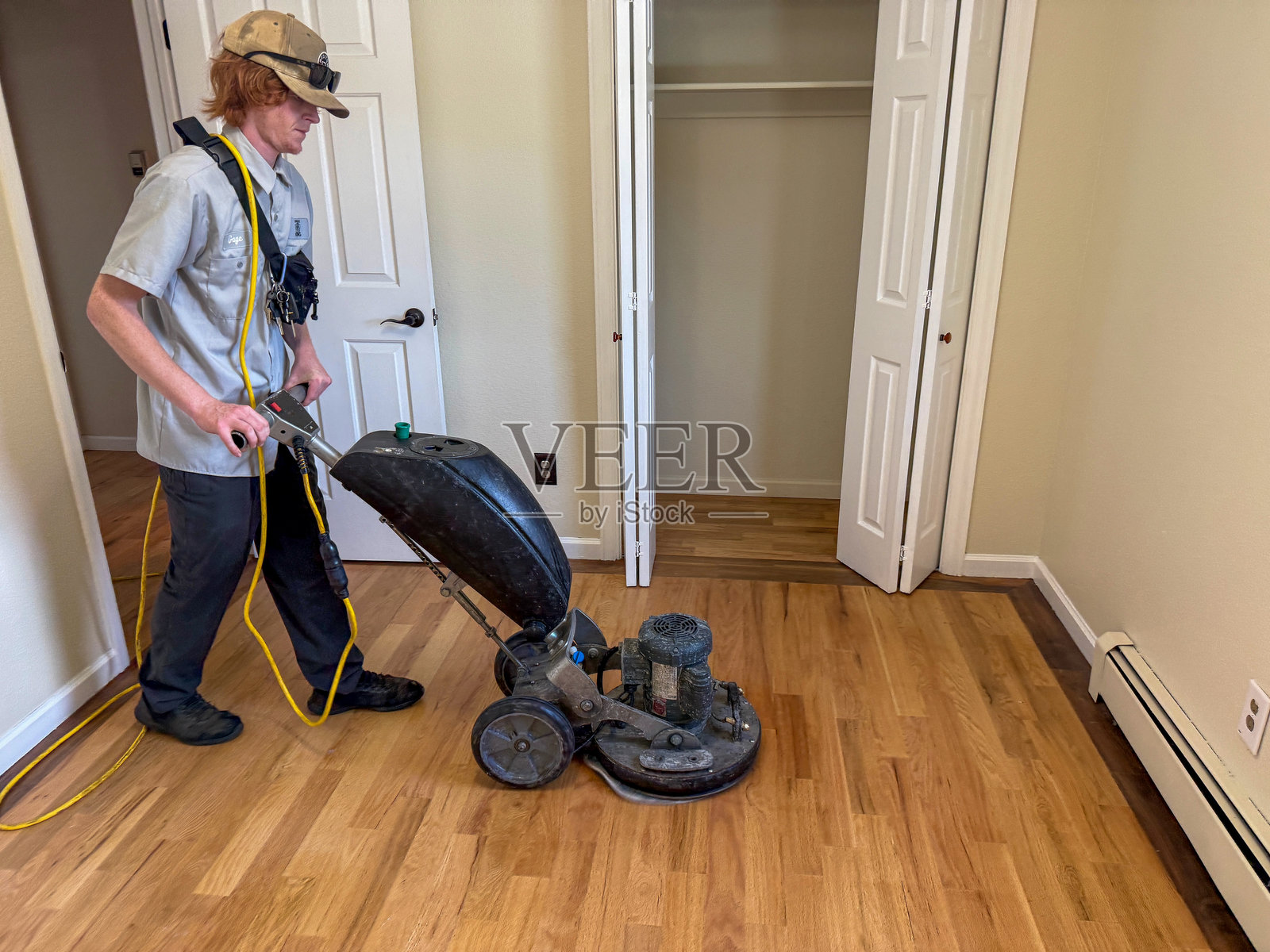 专业地板技师在空房间内打磨硬木地板照片摄影图片