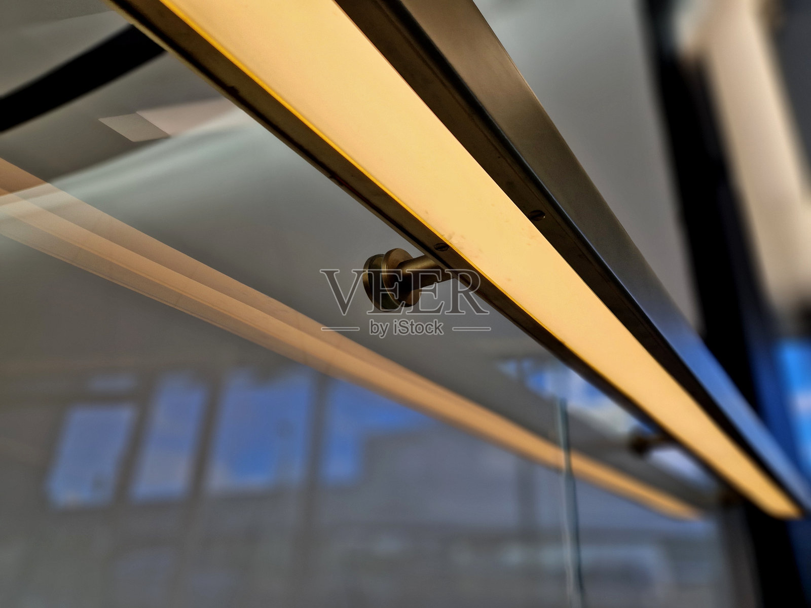 从把手底部有一个凹陷的LED灯带，发出黄色光。楼梯扶手的侧面由无框的粘合玻璃面板制成。金属角落上有不锈钢扶手杆。照片摄影图片