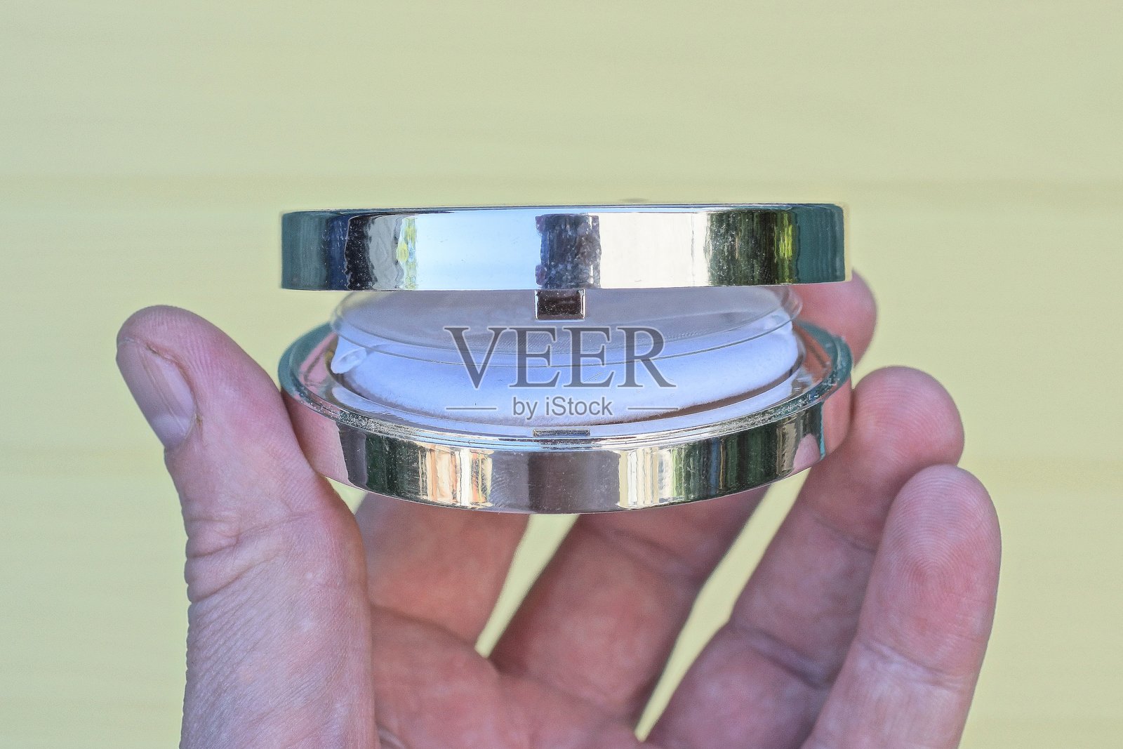 手握一个小型开放的圆形塑料盒子照片摄影图片