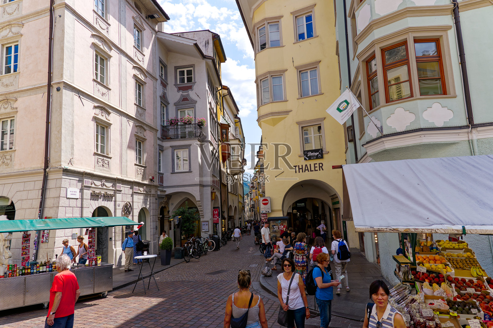 在阳光明媚的夏日，游客们在意大利城市博岚的老城区小巷中漫步。照片摄影图片