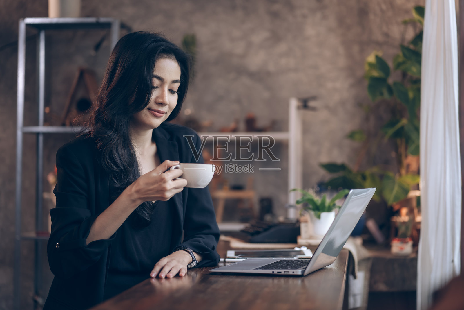 女商人在咖啡店里喝咖啡、使用智能手机，享受放松时光。年轻女性坐着，面带微笑，感到快乐。照片摄影图片