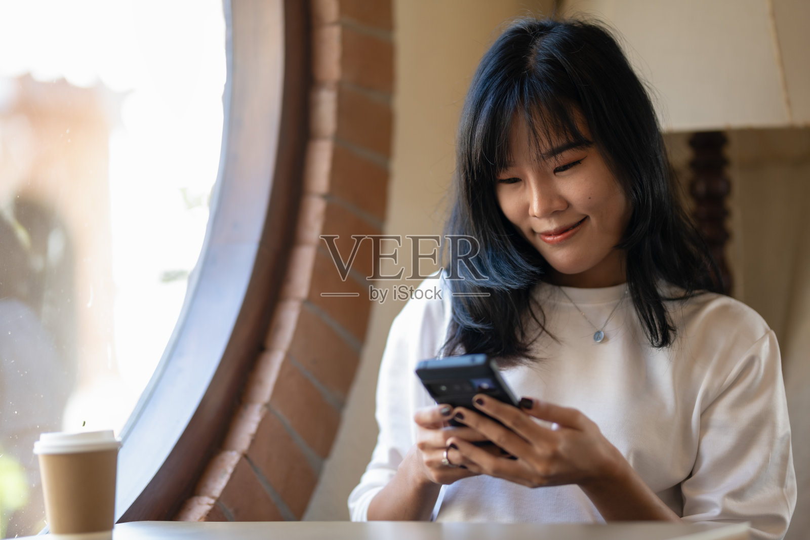 快乐的年轻女性在咖啡店使用智能手机，作为自由职业者工作，聊天或查找信息。照片摄影图片