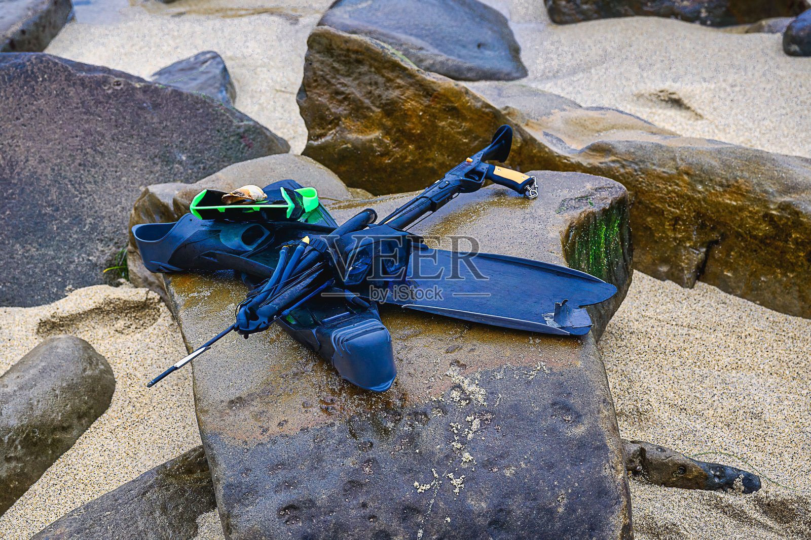 在拉霍亚海湾附近的黑色岩石和沙滩上放着鱼叉钓具和脚蹼照片摄影图片