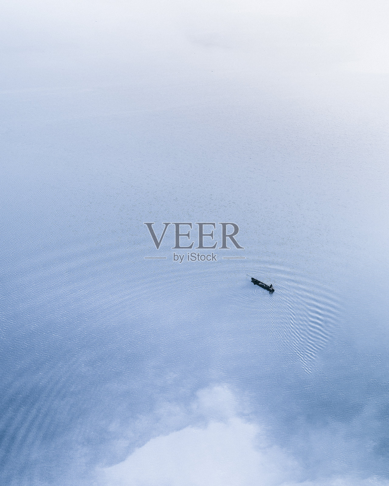 一幅极简主义的鸟瞰图，展示了一只孤独的船只漂浮在广阔的水面上。船只位于右下角，营造出一种平衡与孤独的感觉。照片摄影图片