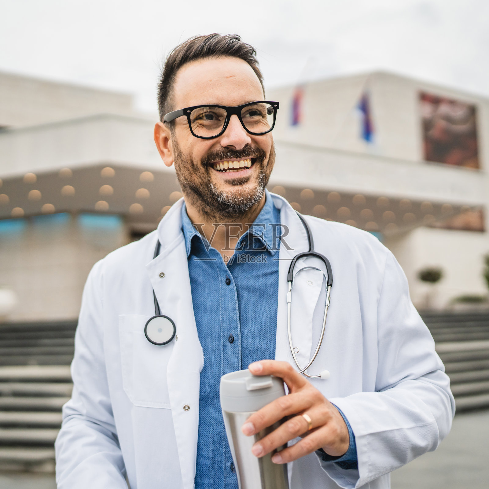 医生在咖啡休息时手持夹板和保温杯的肖像照片摄影图片