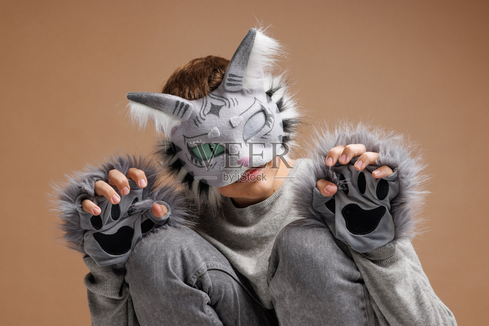 四足健身肖像，穿着猫面具的青少年在米色背景下，摄影棚照片。照片摄影图片