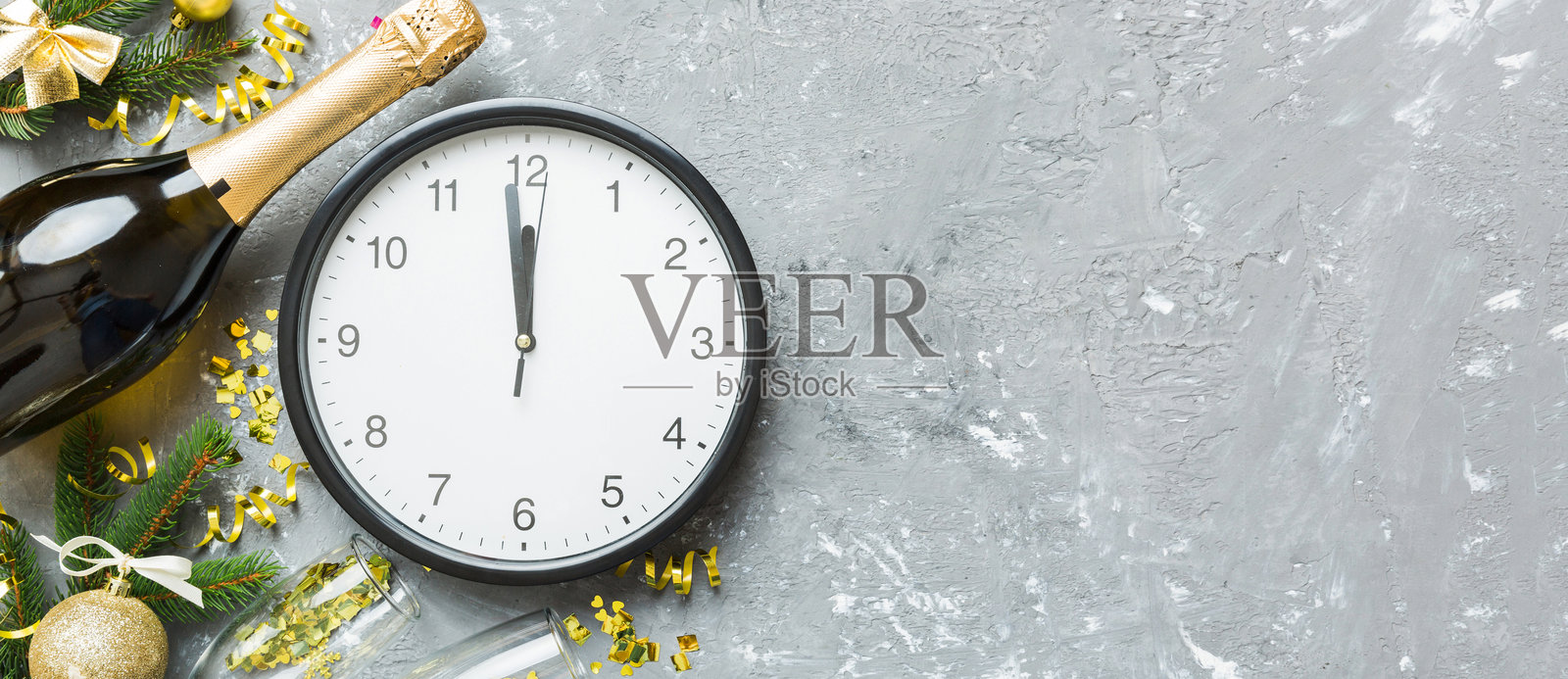 新年庆祝概念，香槟酒瓶和两个祝酒的酒杯。彩色桌子上的圣诞礼品盒、闹钟和松树枝。俯视图，留白空间。照片摄影图片