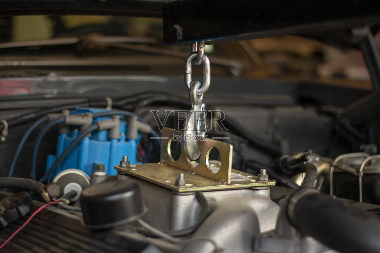 机械师在车库中使用专业升降设备修理和恢复车辆发动机，专注于维修任务照片摄影图片