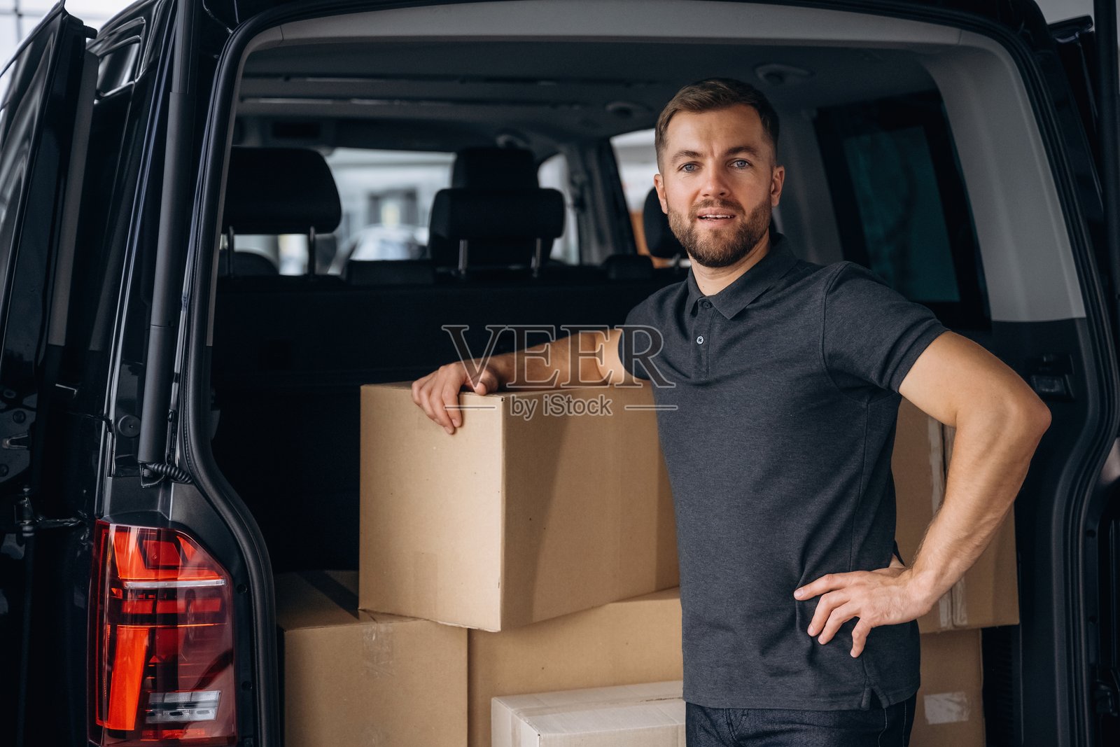 一堆箱子。送货员或装卸工在车旁。照片摄影图片