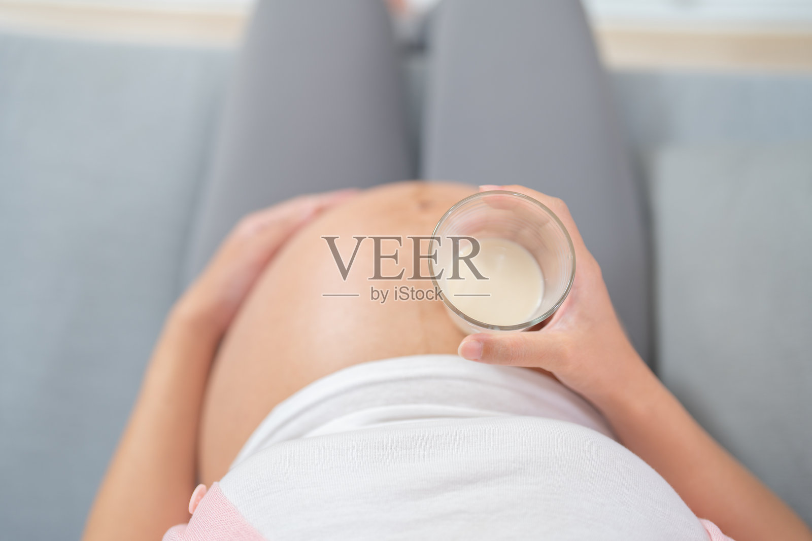 一位快乐的亚洲孕妇在家卧室里喝牛奶补充钙质。期待宝宝的到来。家庭生活方式。母亲的爱。照片摄影图片