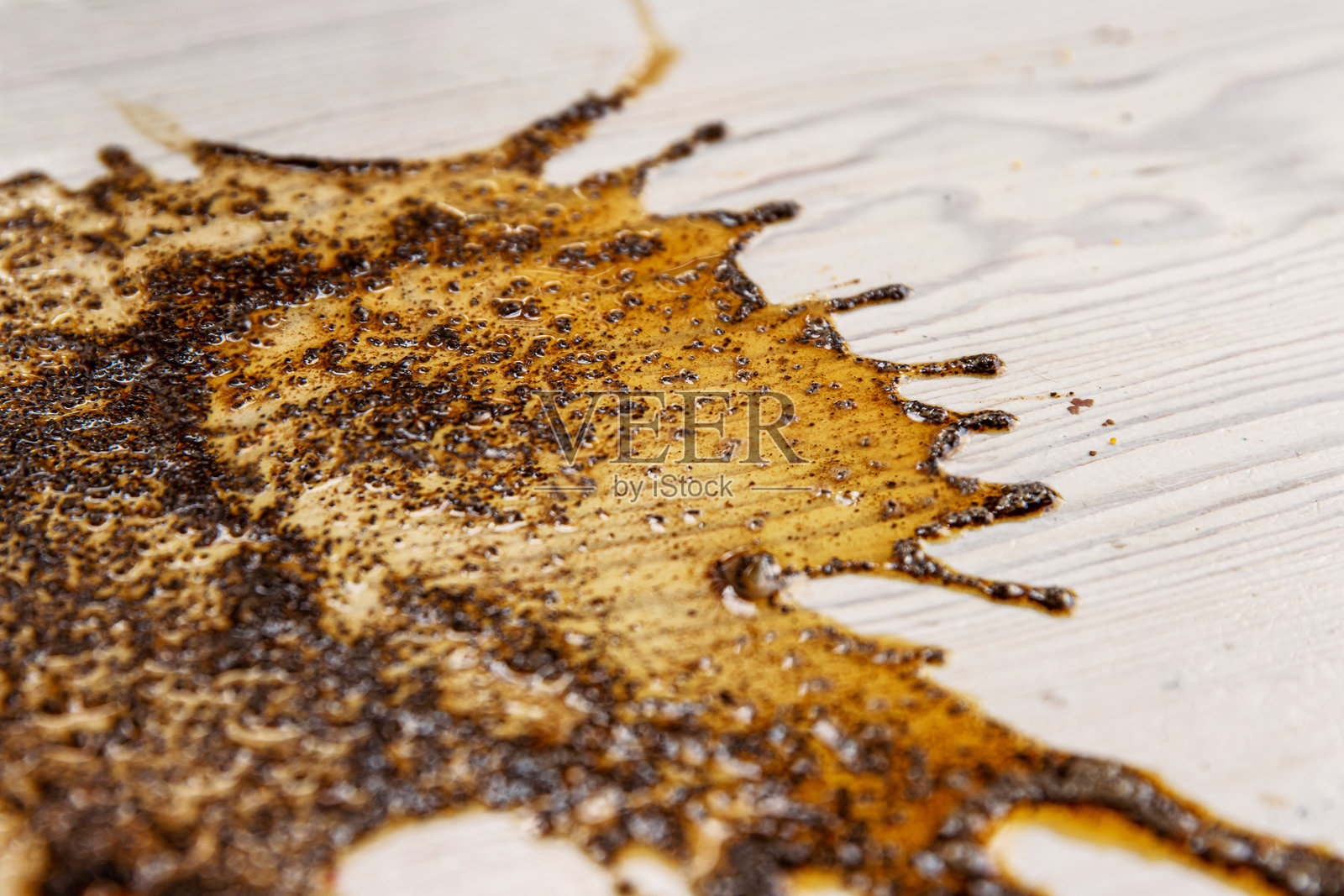 在浅色木质表面上洒落的液体咖啡或酱汁的抽象溅洒，形成有机的不规则图案。留白空间照片摄影图片