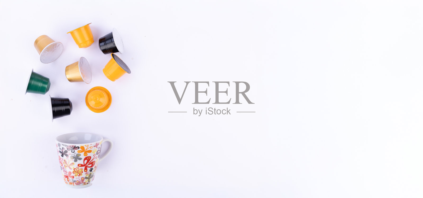 五颜六色的咖啡胶囊和一只杯子在白色背景上照片摄影图片