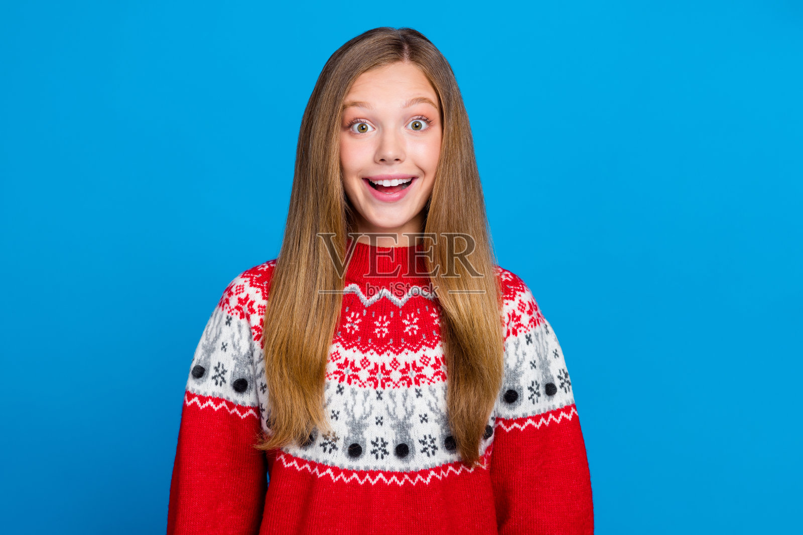 惊讶的积极女孩穿着红色印花毛衣，对低价折扣优惠感到印象深刻，背景为蓝色。照片摄影图片