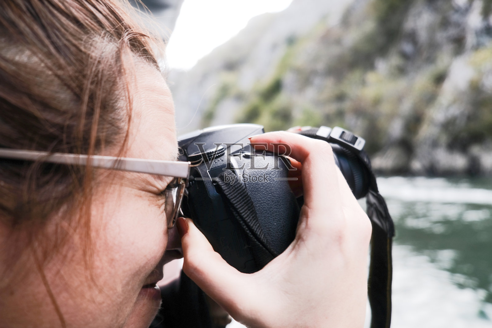 户外山间河边，一位女性摄影师正在用单反相机拍照的特写镜头照片摄影图片