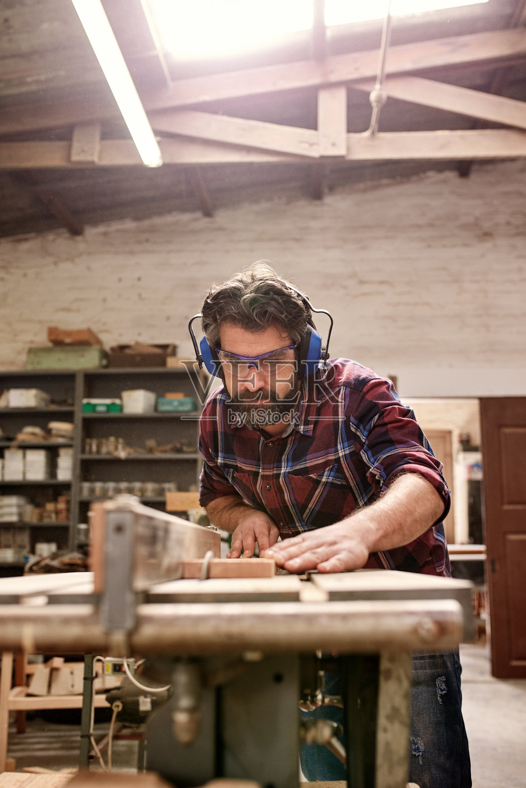 工匠在他的工作坊里佩戴安全装备切割木板照片摄影图片
