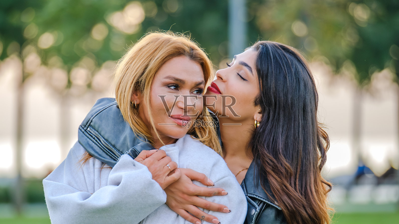 一位年轻的棕发女性在夏日的草地公园里与母亲一起摆姿势并享受乐趣照片摄影图片