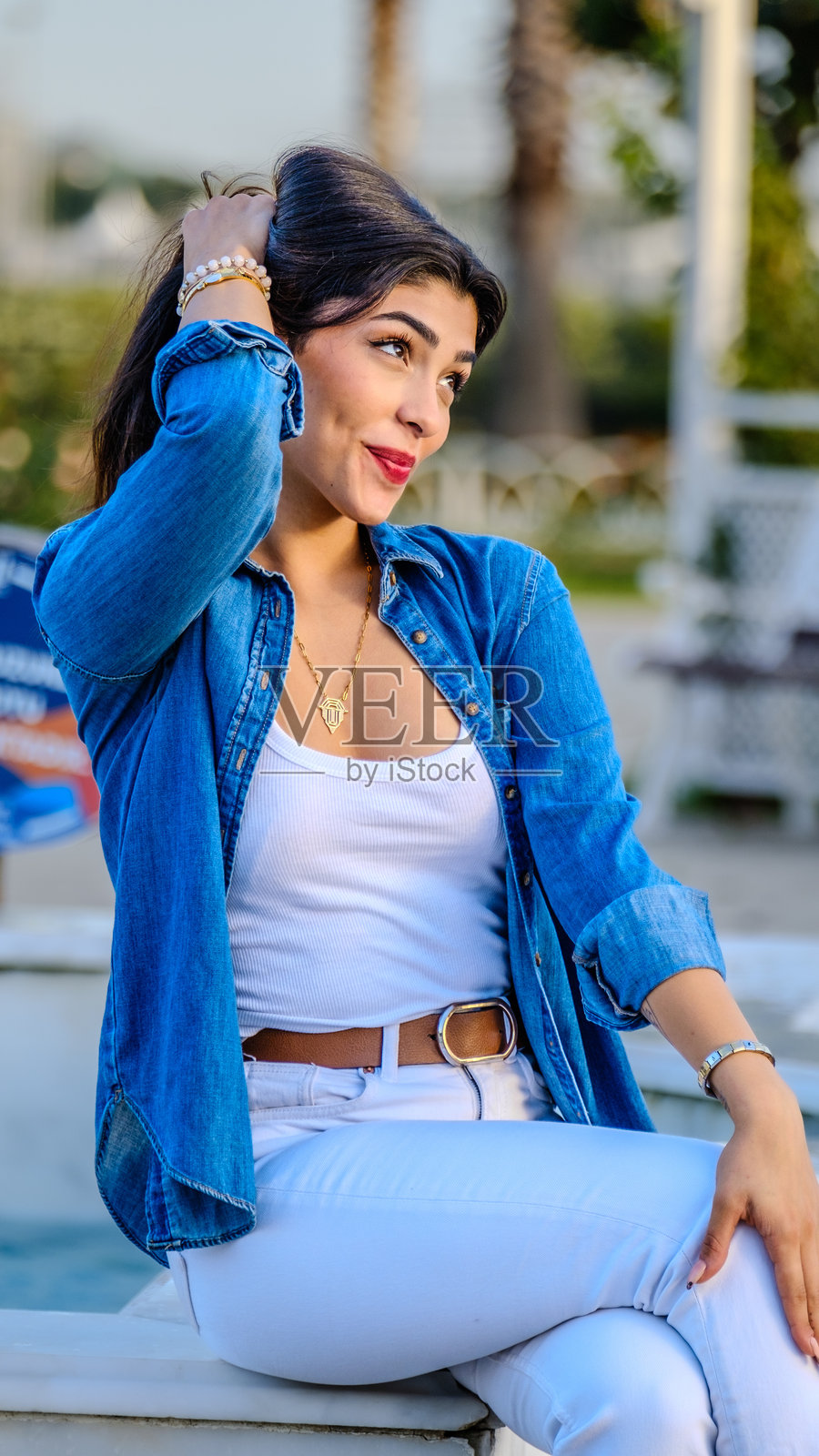 一位美丽的年轻棕发女性在阳光明媚的树木繁茂的公园里为镜头摆姿势照片摄影图片