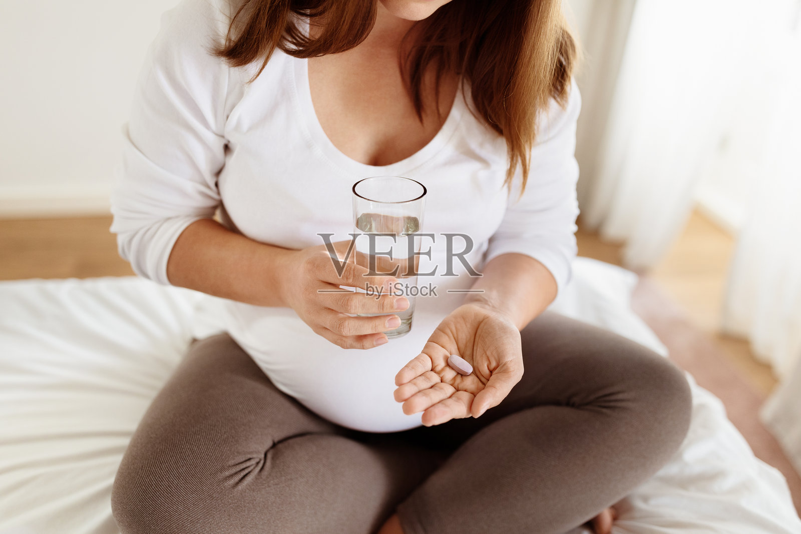 孕妇坐在床上喝水服用产前维生素照片摄影图片