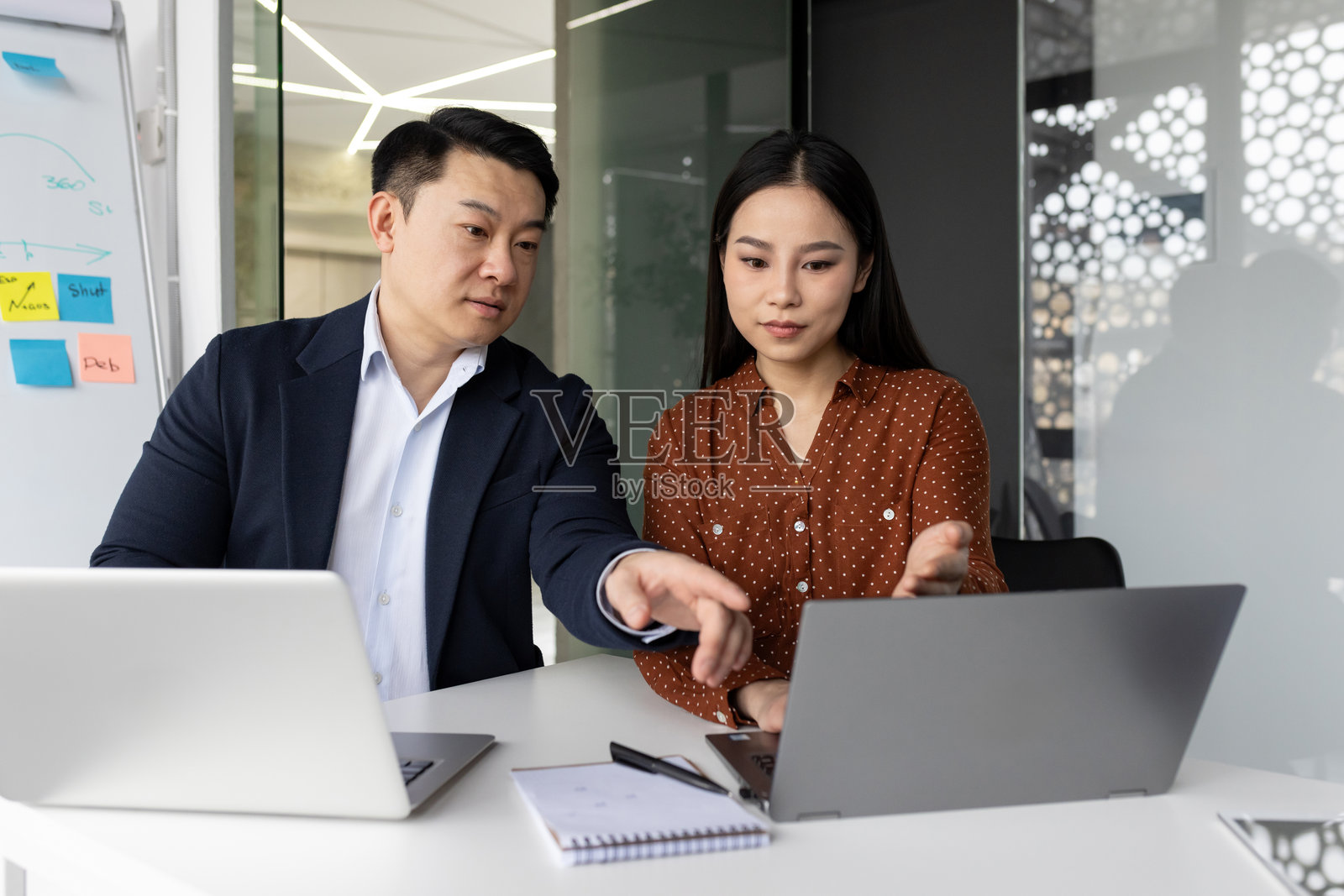 专业商务同事在现代办公室会议中讨论战略，手中拿着笔记本电脑。照片摄影图片