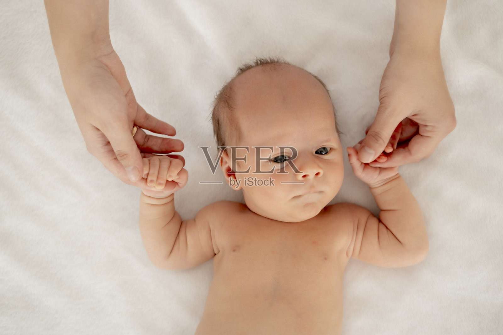 妈妈的手抱着婴儿，刚出生的宝宝在白色背景下睁着眼睛，留有文字空间，特写宝宝的肖像。照片摄影图片