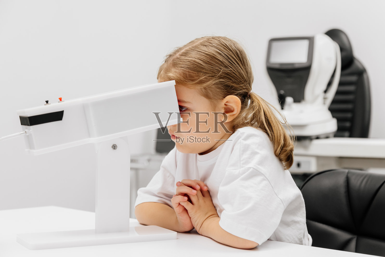 一个女孩正在使用尖端设备参与引人入胜的视力增强治疗。这种激光治疗有助于恢复和发展视觉技能。照片摄影图片