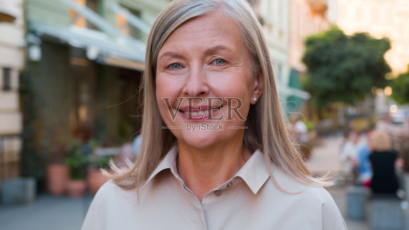 特写肖像，快乐的老年女性，灰白头发，微笑大笑的白人欧洲退休女商人，户外城市街道上看着镜头，露出洁白的牙齿微笑。照片摄影图片
